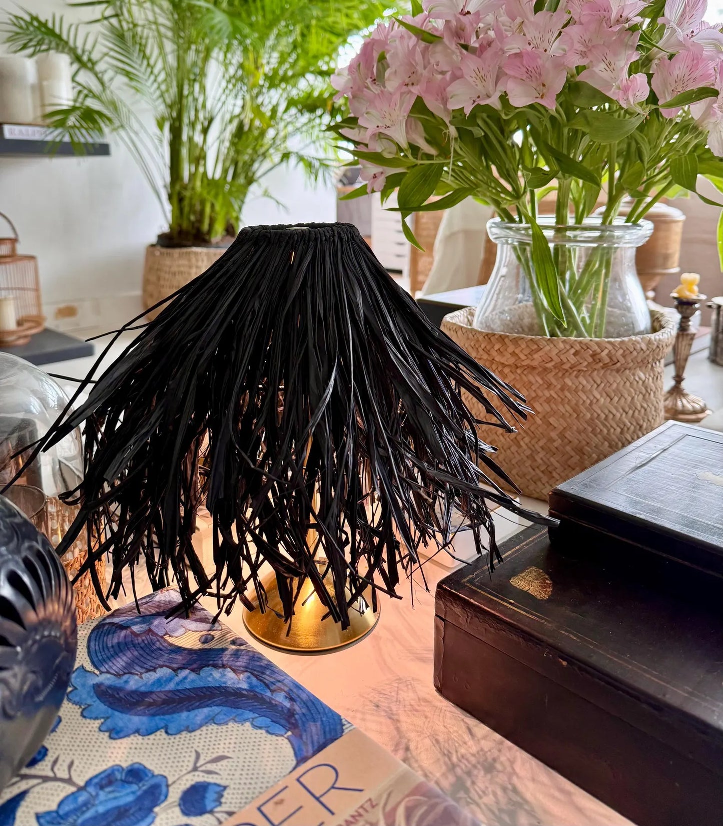 Lit black raffia shade providing fire-safe ambient light on a cordless lamp for a warm evening lounge glow.