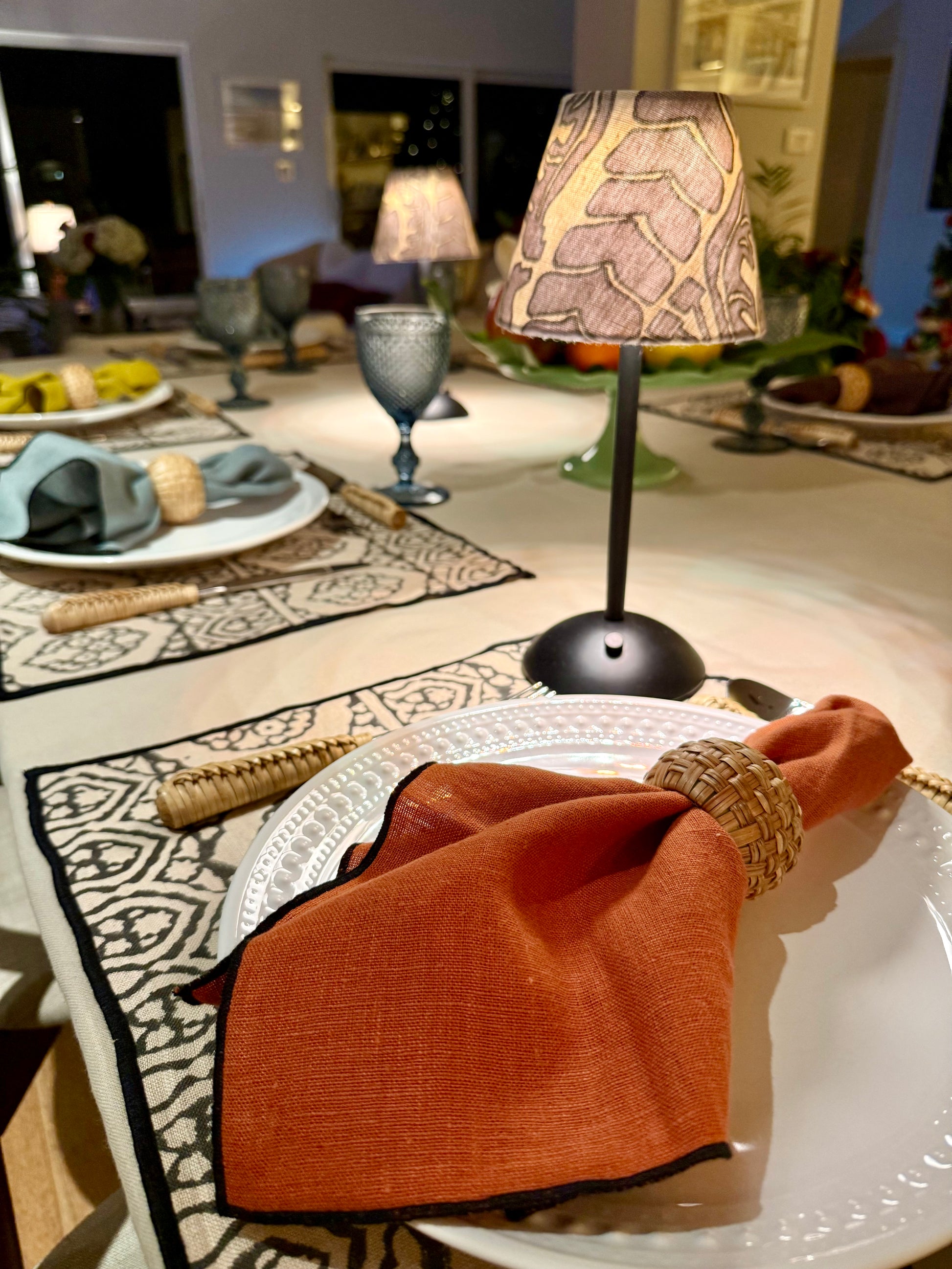 Designer tablescape detail with a lit Scalamandré botanical lamp shade on a black cordless lamp.