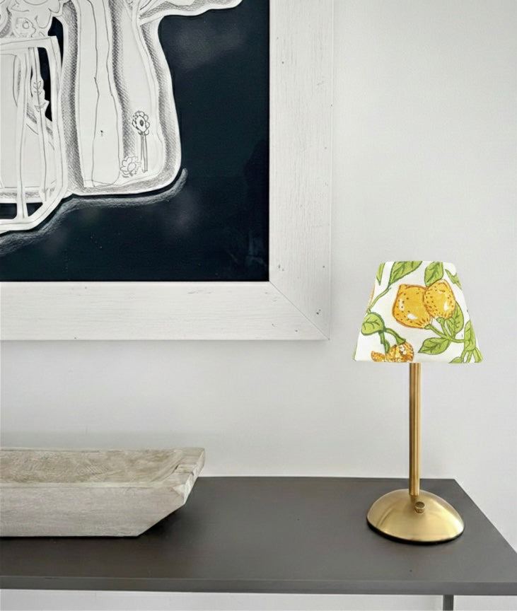 The Lemon citrus print shade for a cordless lamp styled on a minimalist black console table beneath large-scale art.