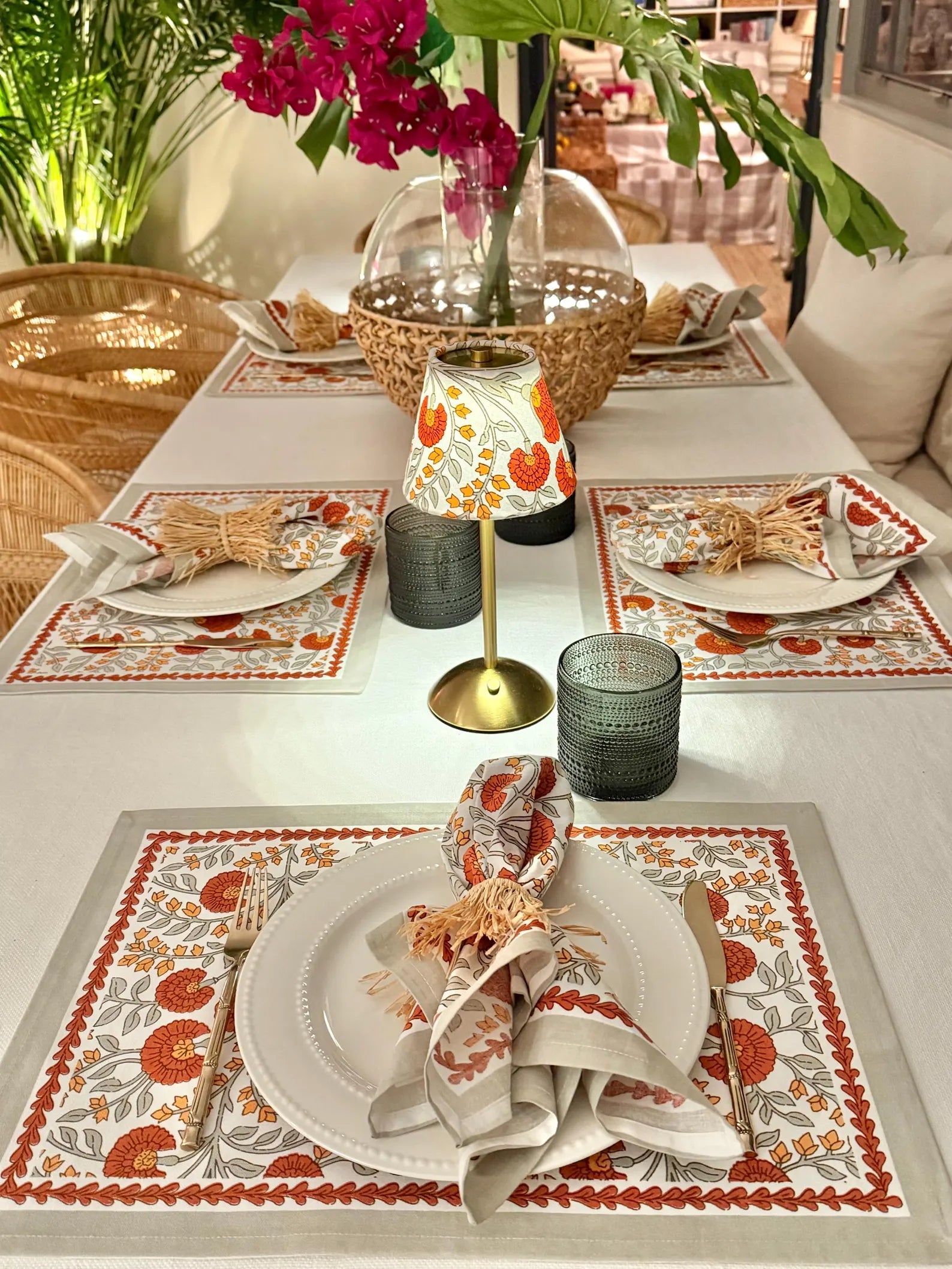Table setting featuring Marigold floral lamp shades on a cordless table lamp, rattan chairs, and a tropical centerpiece, styled for a bright and cheerful dining look
