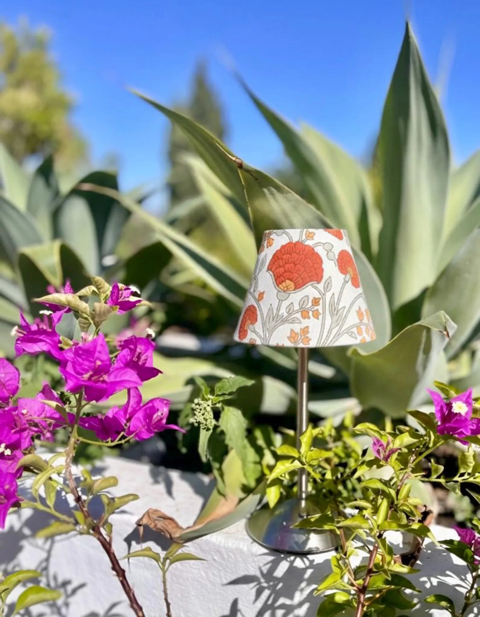 marigold floral lamp shade on a silver cordless table lamp styled outdoors with agaves and vibrant bougainvillea