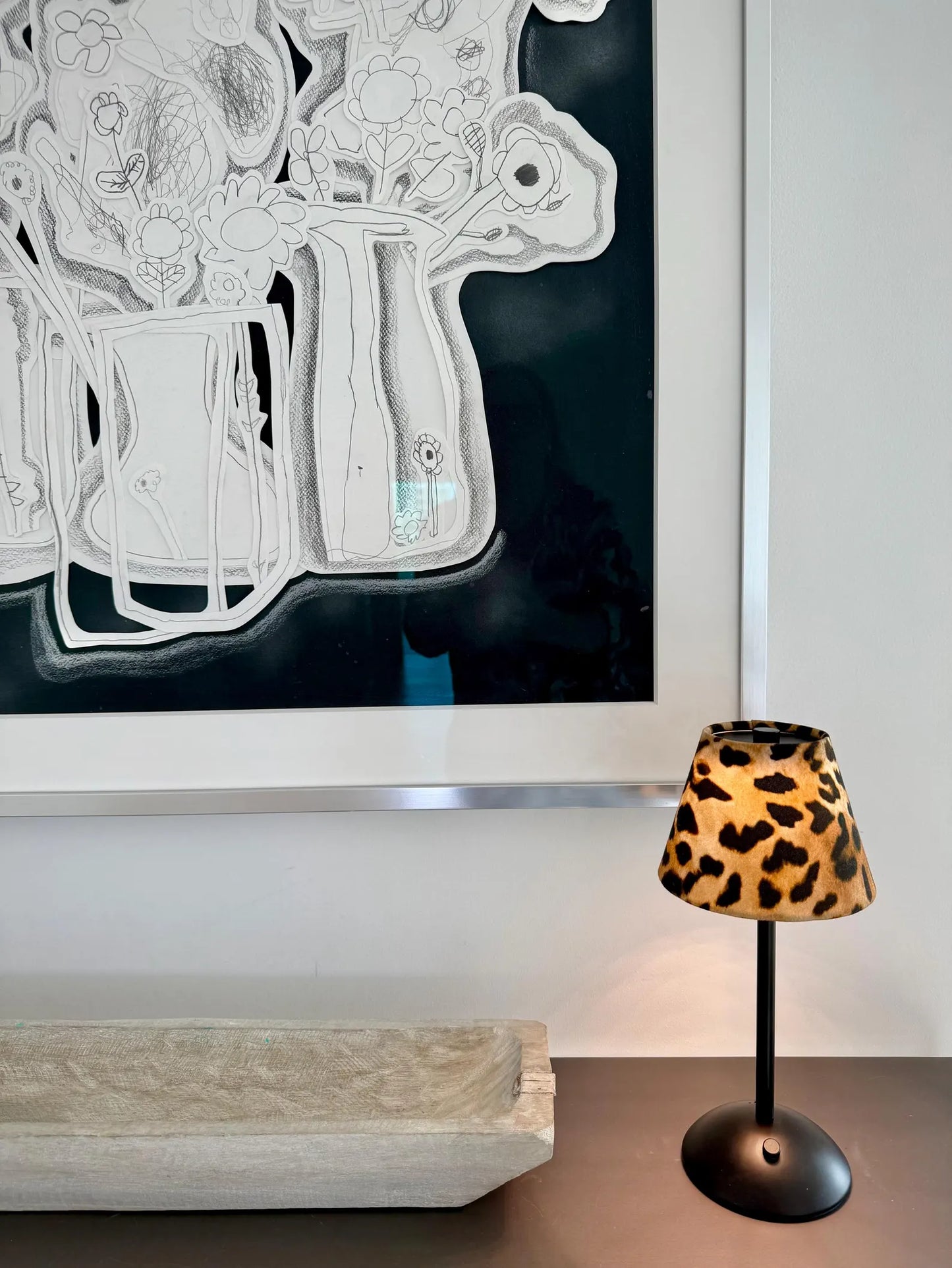 Handcrafted leopard floral shade on a black cordless lamp styled on a console with high-end architectural decor.