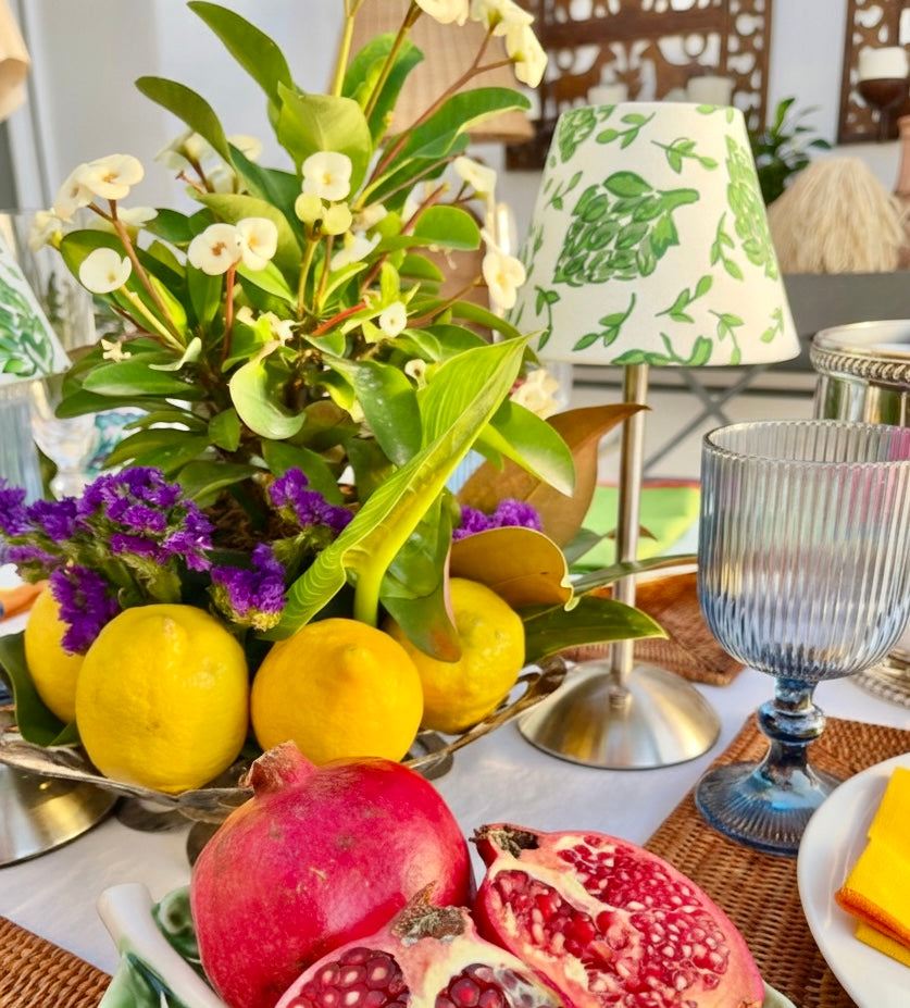 Green and white artichoke print shade styled with lemons and pomegranates for a vibrant tablescape.