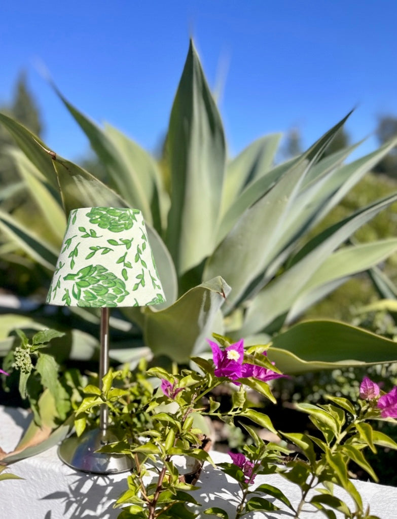Botanical artichoke lampshade styled outdoors with agave plants and warm ambient lighting.