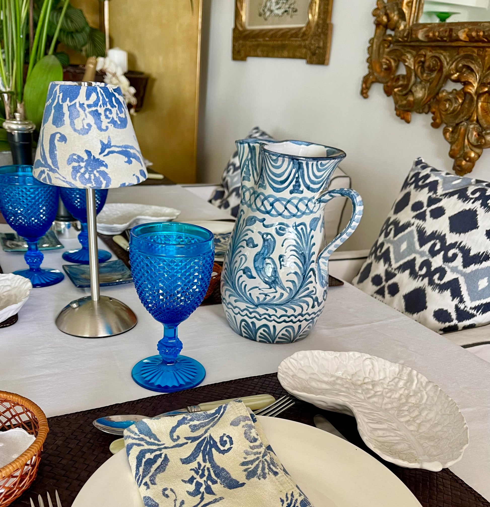 Boutique Ralph Lauren lampshade on a silver cordless base beside a blue and white patterned pitcher and glassware.