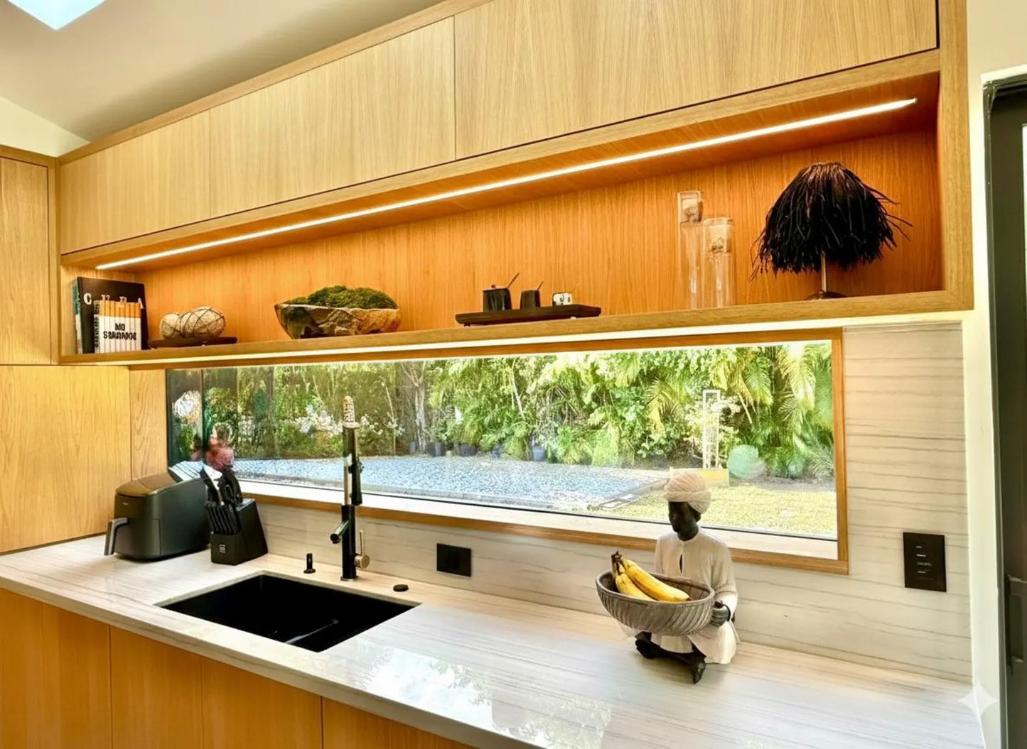 Handcrafted black raffia lampshade on a cordless lamp styled on a minimalist wooden kitchen shelf.
