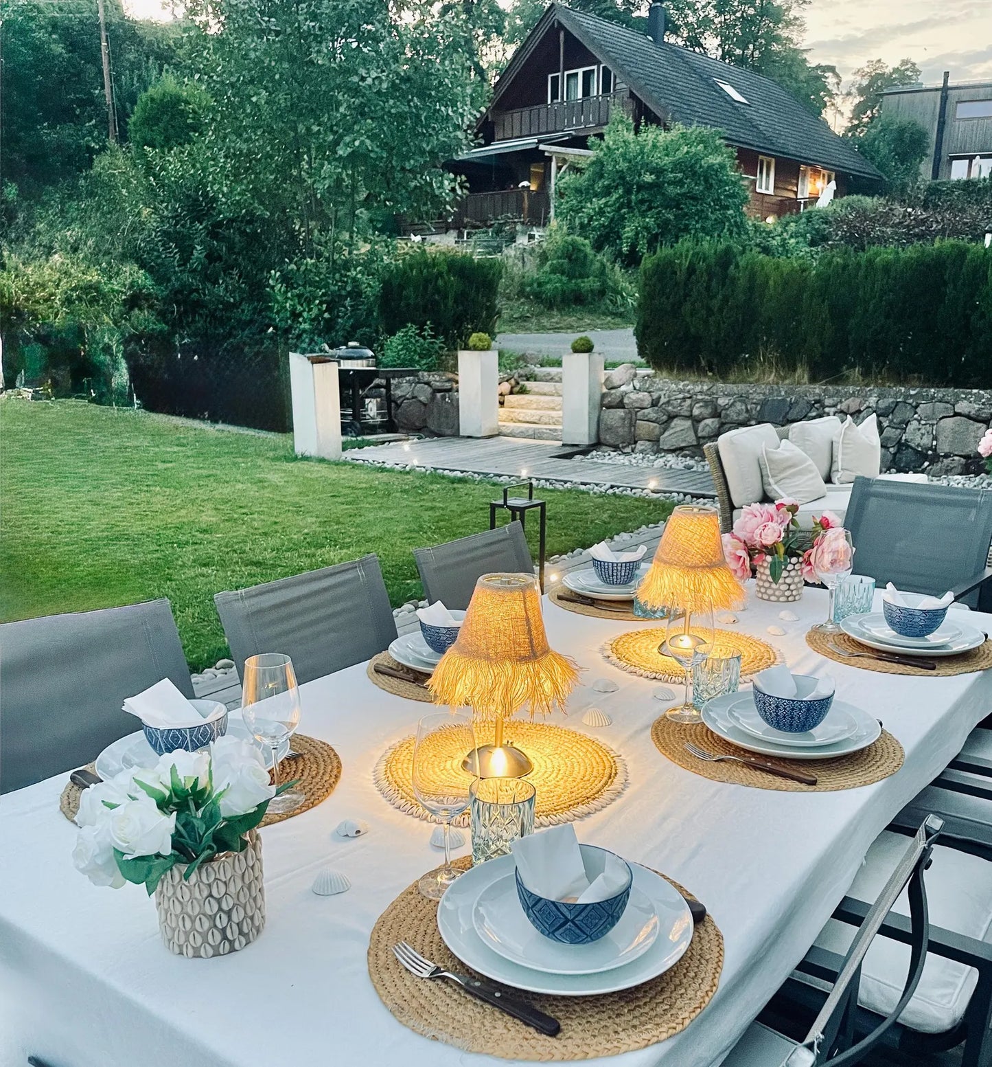 Night tablescape with burlap fringe shades on cordless lamps providing fire-safe ambient lighting for outdoor garden dining.