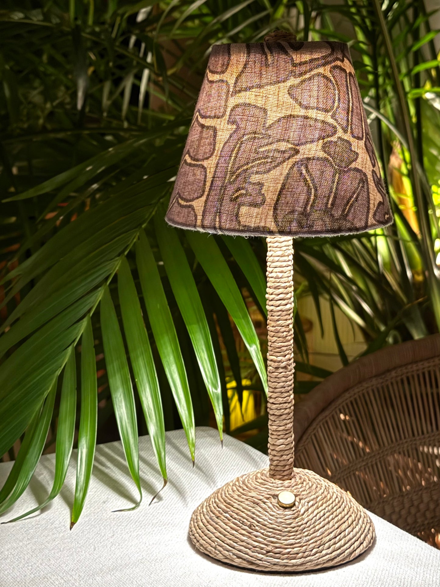 Handcrafted Scalamandré floral shade on a cordless lamp base styled outdoors with tropical palms.