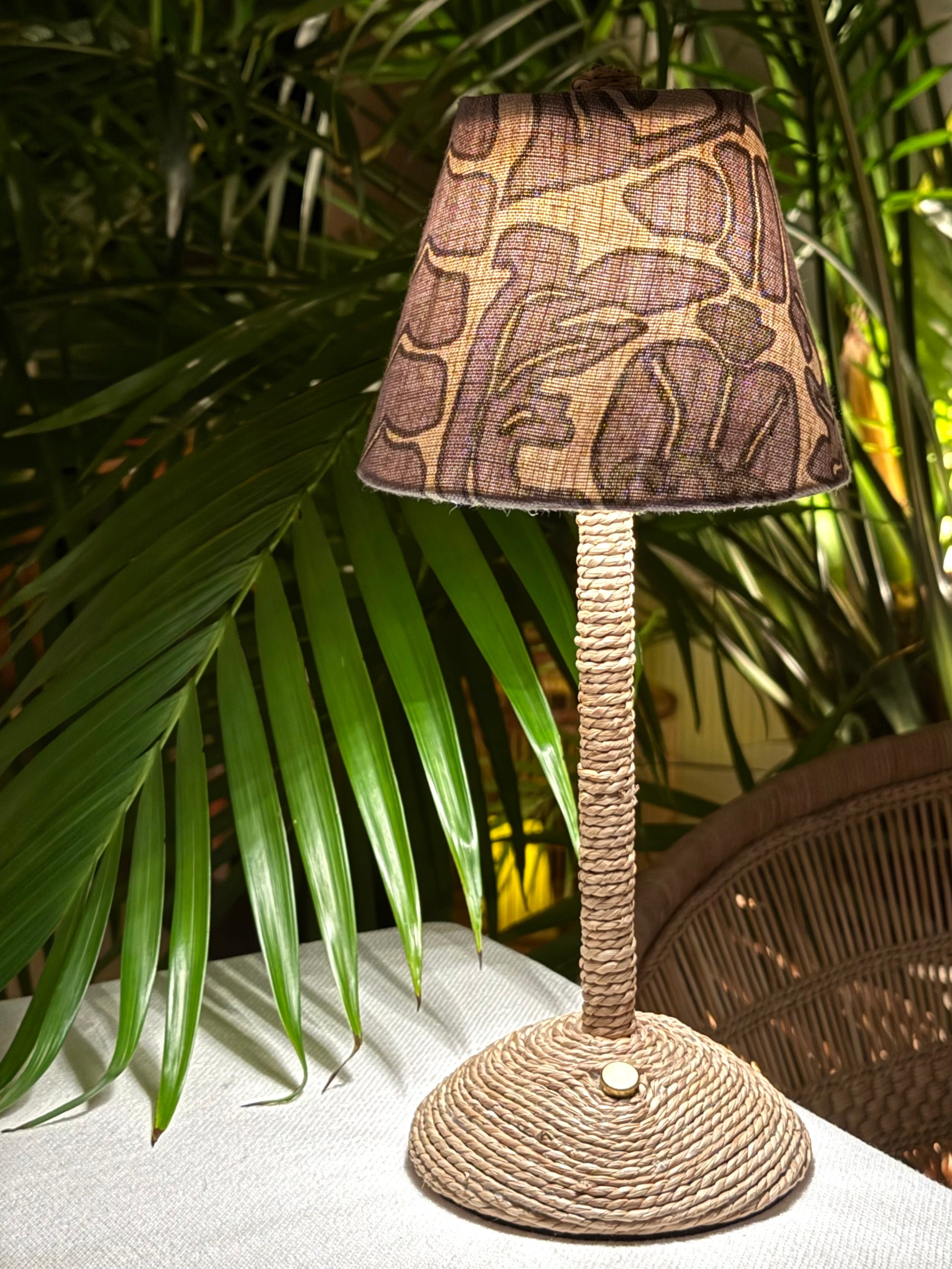 Handcrafted Scalamandré floral shade on a cordless lamp base styled outdoors with tropical palms.