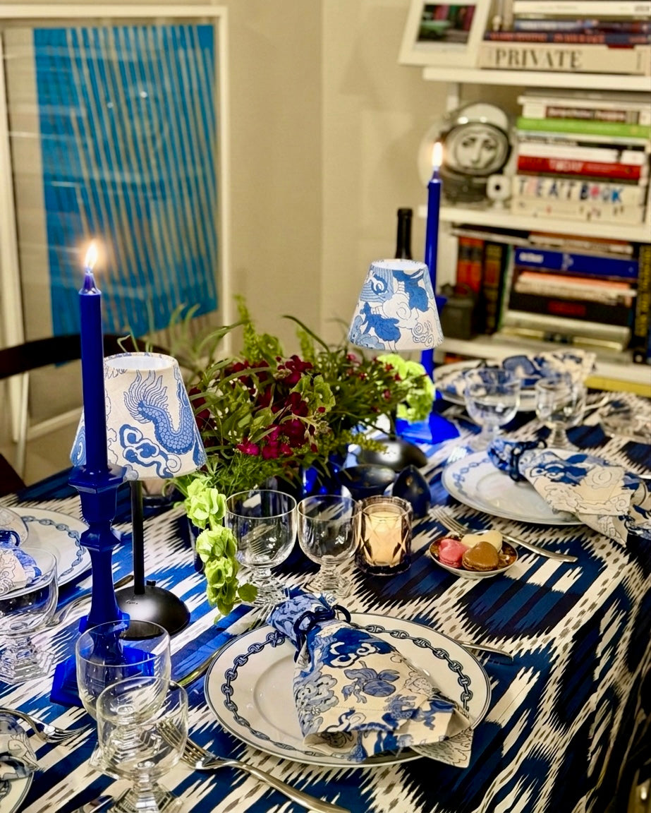 High-end blue and white tablescape featuring ikat linens, sapphire glassware, and handcrafted Schumacher blue dragon linen lamp shades